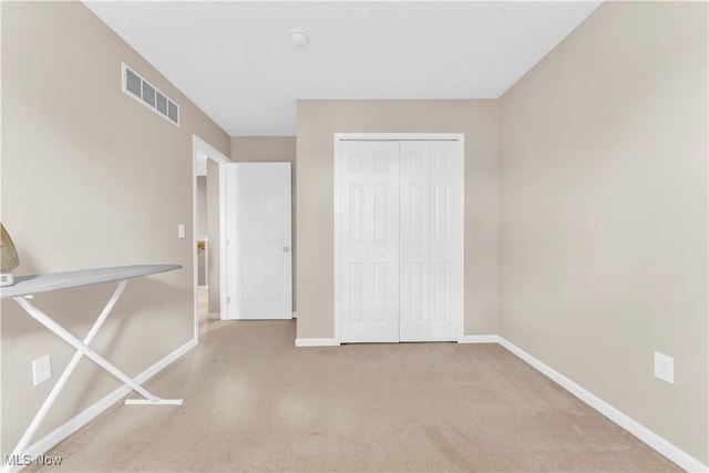 unfurnished bedroom featuring baseboards, visible vents, carpet, and a closet