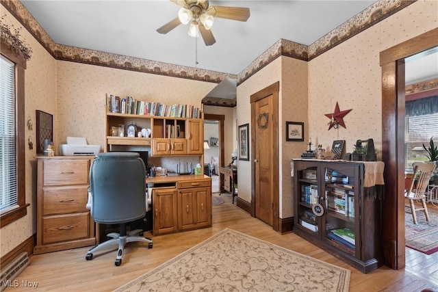 home office with plenty of natural light, a ceiling fan, wallpapered walls, and light wood-style flooring