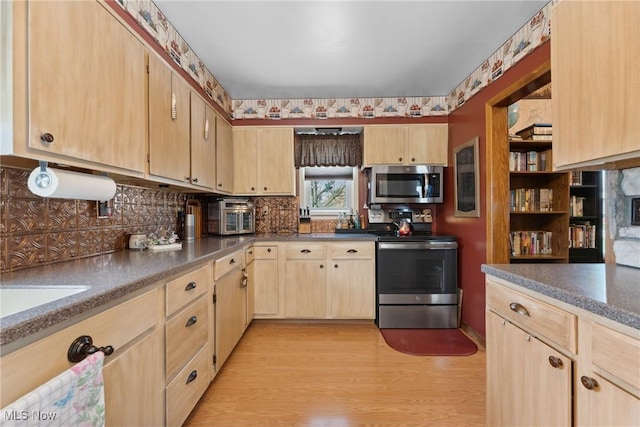 kitchen with light brown cabinetry, stainless steel appliances, decorative backsplash, and light wood finished floors