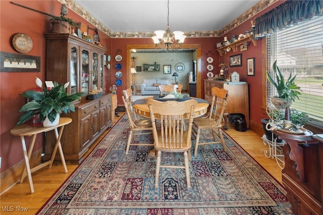 dining room featuring baseboards, light wood-type flooring, and a notable chandelier