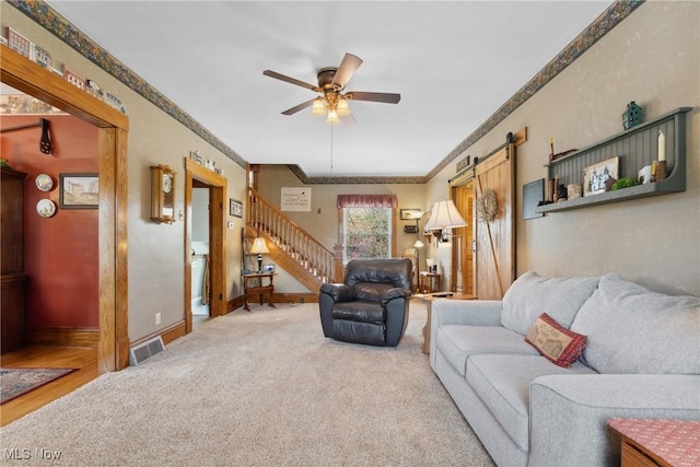 living area with a ceiling fan, visible vents, stairway, ornamental molding, and carpet