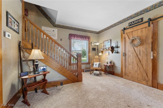 carpeted entryway featuring baseboards, a barn door, stairs, and visible vents
