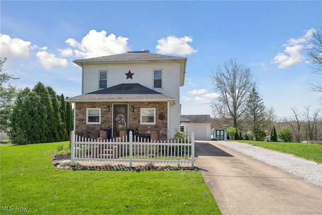 view of front of house with fence, stone siding, a garage, a front yard, and an outdoor structure