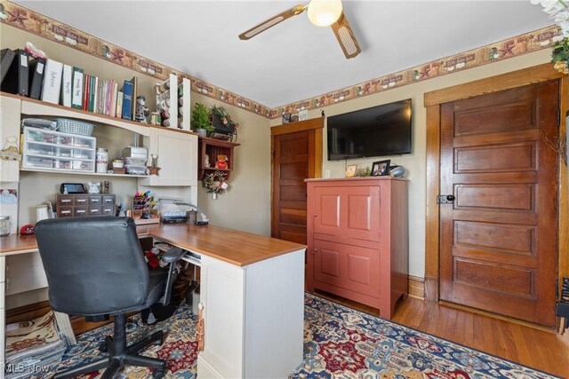 office area featuring ceiling fan, wood finished floors, and built in study area