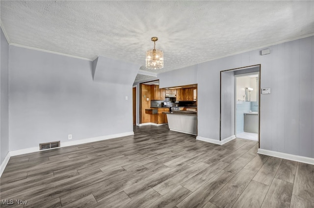 unfurnished living room featuring visible vents, a textured ceiling, dark wood-type flooring, and a chandelier