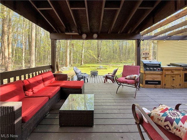 deck with outdoor lounge area, a forest view, and area for grilling