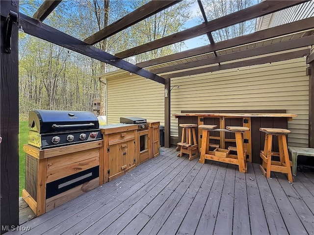 wooden deck featuring outdoor dry bar, a pergola, and a grill