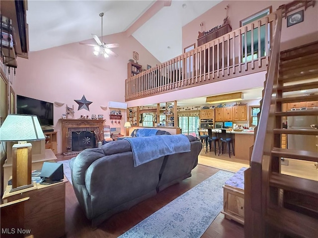 living room featuring a brick fireplace, high vaulted ceiling, ceiling fan, and wood finished floors