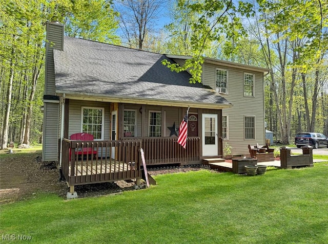 back of house with roof with shingles, a chimney, and a yard
