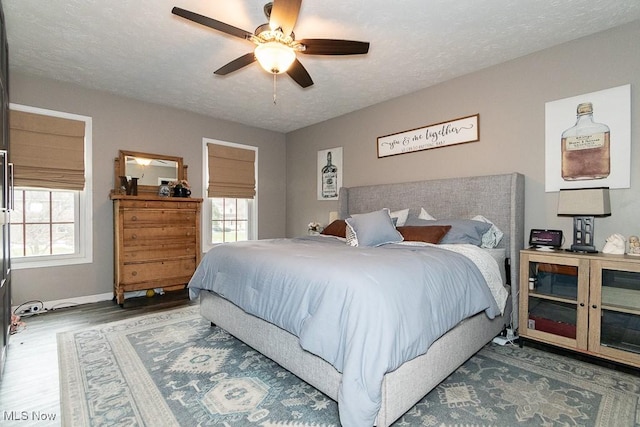 bedroom with a textured ceiling, multiple windows, and wood finished floors