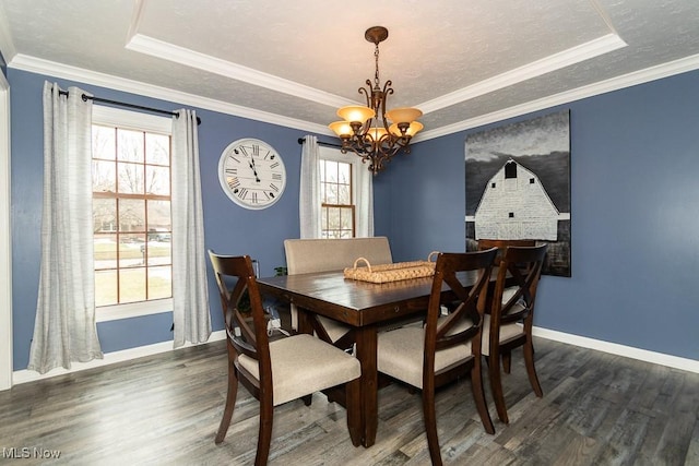 dining room featuring an inviting chandelier, crown molding, wood finished floors, baseboards, and a raised ceiling