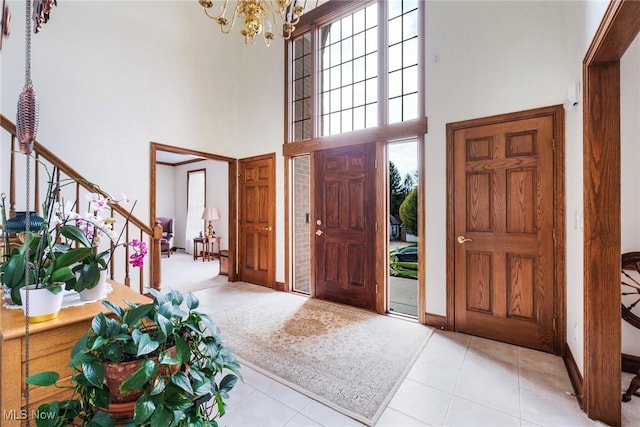 tiled foyer with stairs, baseboards, a chandelier, and a towering ceiling