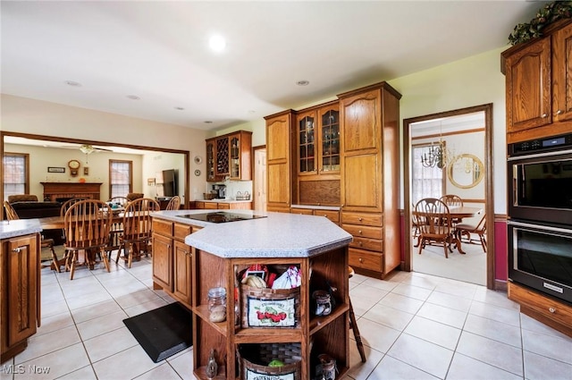kitchen with black electric cooktop, open shelves, multiple ovens, and light tile patterned floors