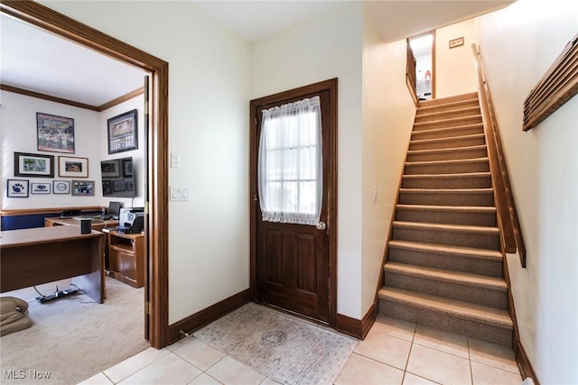 foyer featuring stairs, baseboards, light carpet, and light tile patterned floors