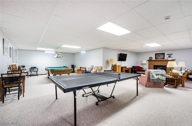 recreation room with carpet floors, pool table, a paneled ceiling, and a brick fireplace