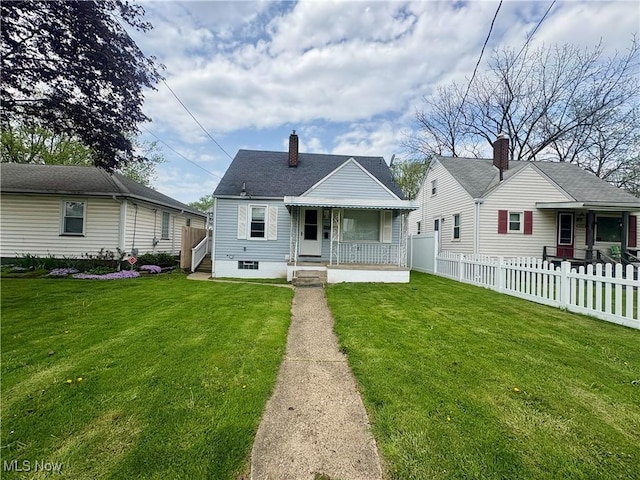 back of house with a yard, a chimney, fence private yard, and a porch
