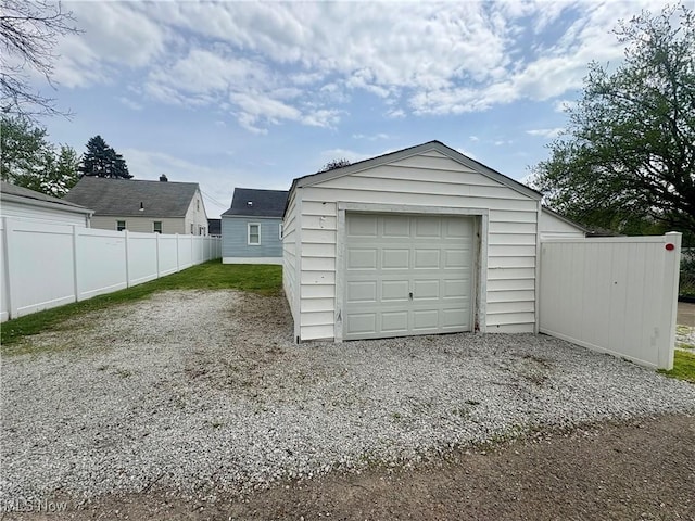 detached garage featuring fence and gravel driveway