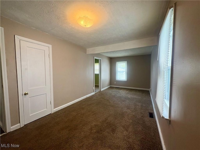 unfurnished bedroom featuring baseboards, carpet, a textured ceiling, and visible vents