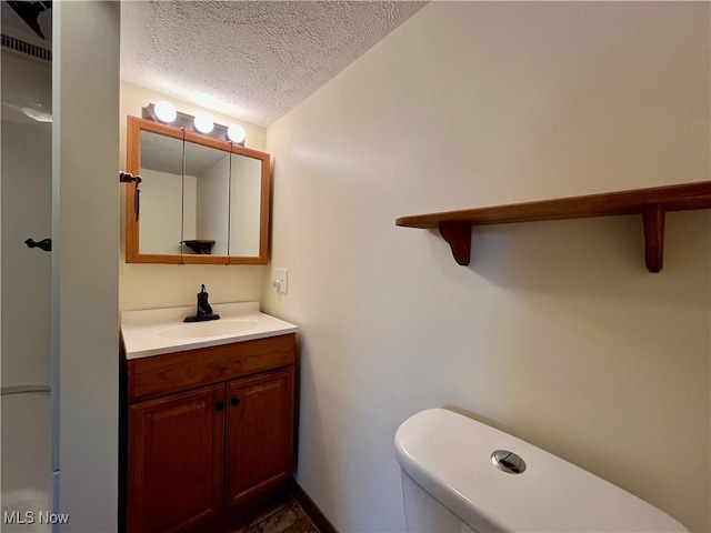 bathroom with vanity, a textured ceiling, and toilet