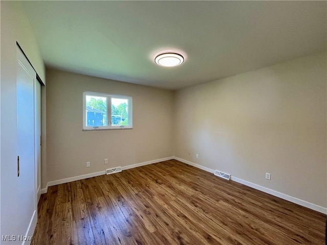 unfurnished bedroom featuring baseboards, dark wood-type flooring, and visible vents