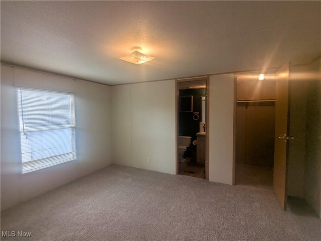 unfurnished bedroom with carpet, a closet, a textured ceiling, and connected bathroom