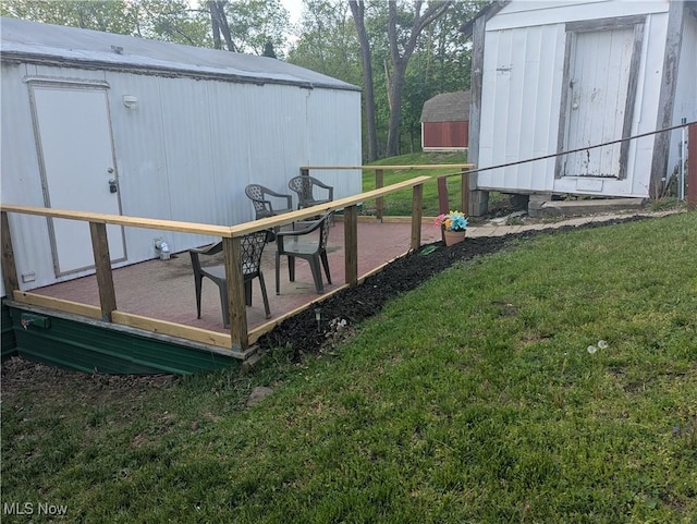 view of yard featuring an outbuilding, a shed, and a wooden deck