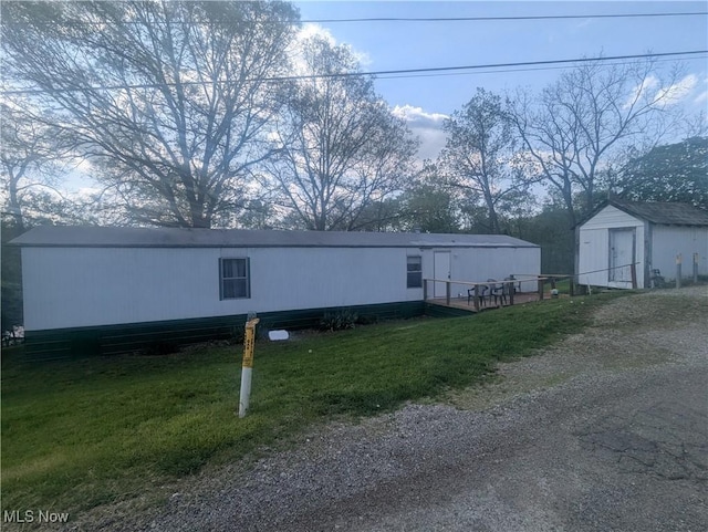 view of side of home with a storage shed, an outdoor structure, and a lawn