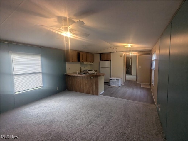 kitchen with freestanding refrigerator, a peninsula, open floor plan, ceiling fan, and carpet