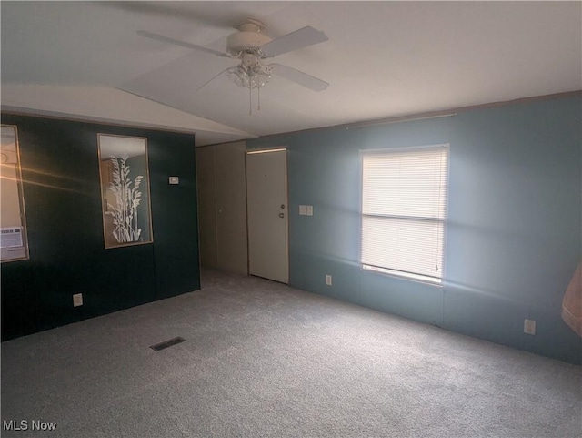 carpeted spare room with visible vents, ceiling fan, and lofted ceiling