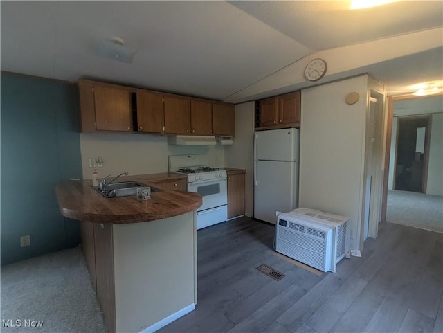 kitchen with brown cabinets, a sink, white appliances, a peninsula, and lofted ceiling