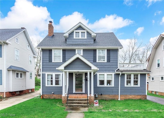 american foursquare style home featuring roof with shingles, a chimney, and a front lawn