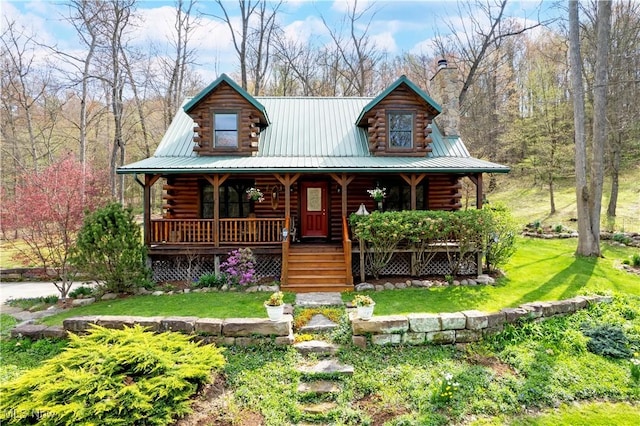 log-style house with a porch, log siding, a front yard, and a chimney