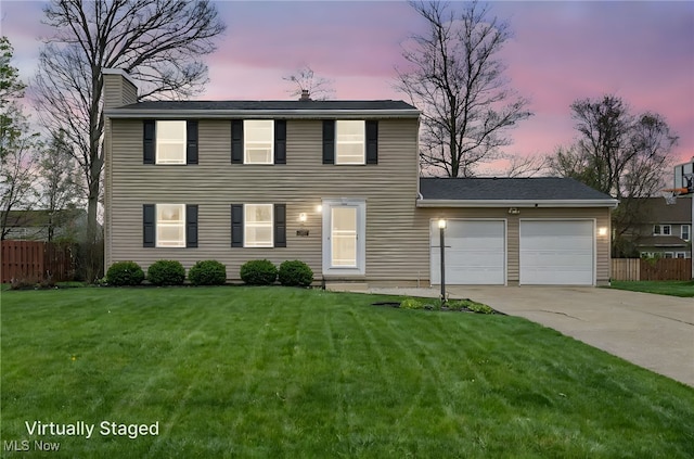 colonial inspired home featuring a chimney, a front yard, a garage, fence, and concrete driveway