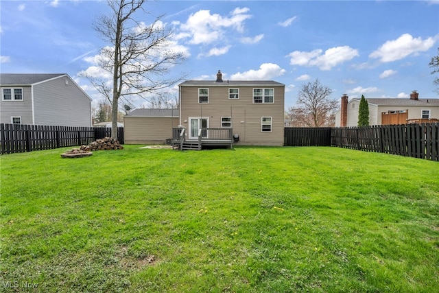 back of property with a fenced backyard, a lawn, and a deck