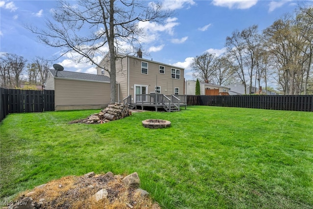back of house with a lawn, a fenced backyard, a fire pit, and a wooden deck