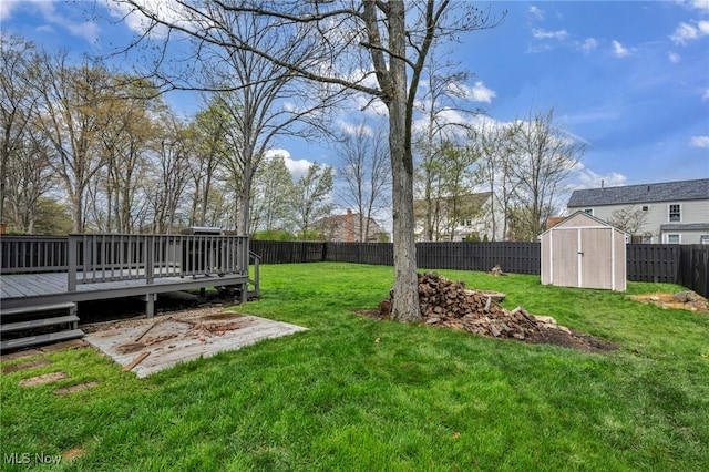 view of yard with a storage shed, an outbuilding, a wooden deck, and a fenced backyard