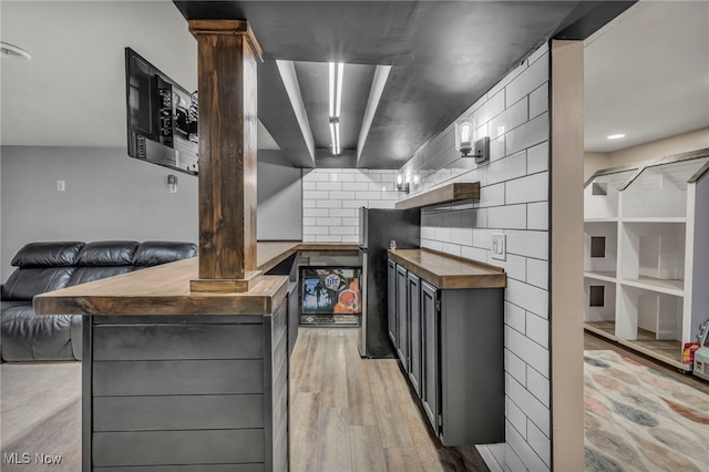 kitchen featuring tasteful backsplash, light wood-type flooring, butcher block counters, and open floor plan