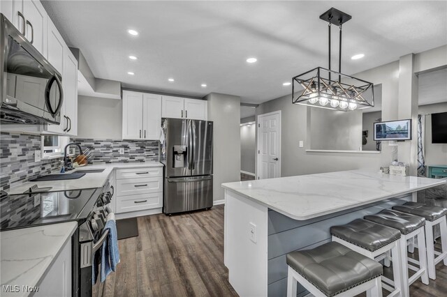 kitchen featuring a sink, light stone counters, stainless steel appliances, and dark wood finished floors