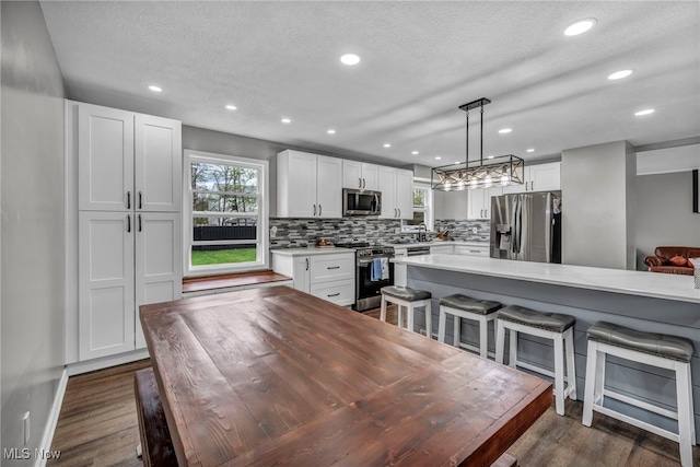 kitchen with white cabinetry, backsplash, a breakfast bar, and stainless steel appliances