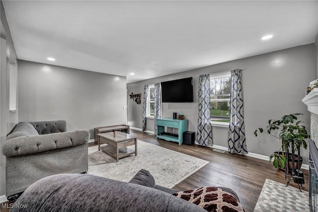 living area featuring baseboards, recessed lighting, wood finished floors, and a fireplace