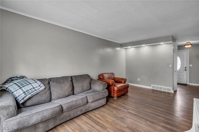 living area featuring visible vents, baseboards, crown molding, and wood finished floors