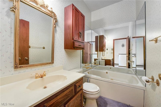 bathroom featuring a jetted tub, vanity, toilet, and wallpapered walls