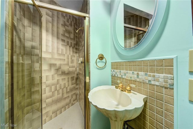 full bathroom featuring wainscoting, tile walls, a shower stall, and a sink