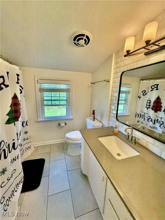 bathroom with visible vents, tile patterned floors, vanity, toilet, and lofted ceiling
