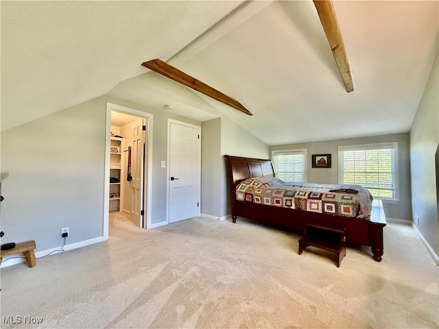 bedroom with carpet flooring, baseboards, a spacious closet, and vaulted ceiling with beams