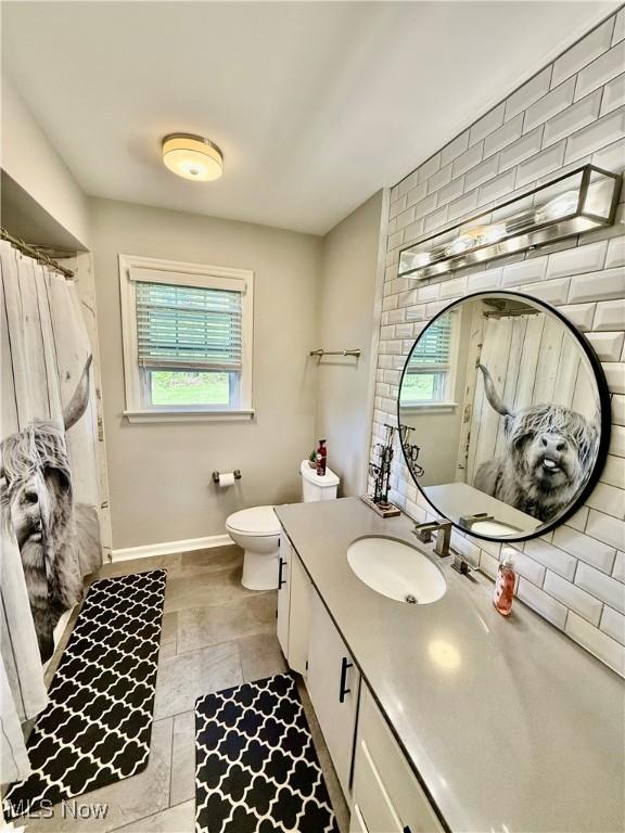 full bathroom featuring vanity, plenty of natural light, baseboards, and toilet