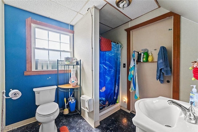 bathroom featuring a sink, toilet, a shower with shower curtain, a paneled ceiling, and baseboards