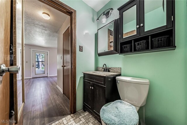 bathroom with vanity, baseboards, toilet, and a textured ceiling