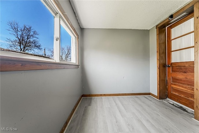 unfurnished room with baseboards, a textured ceiling, and wood finished floors