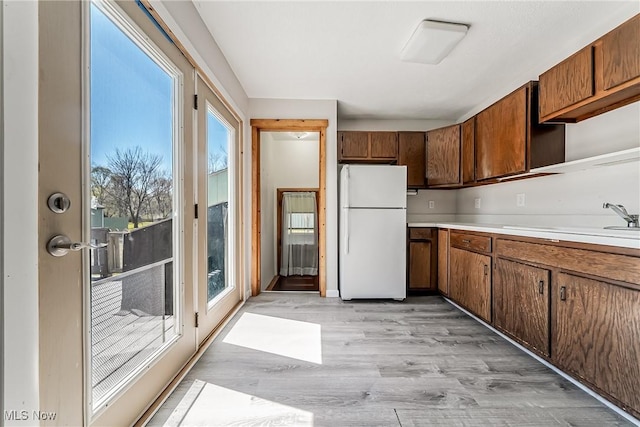 kitchen with freestanding refrigerator, light wood-style flooring, a wealth of natural light, and light countertops